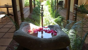 Une fontaine en pierre intégrée à un aménagement paysager.