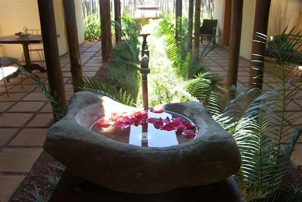 A stone water feature with a fountain in a garden setting.