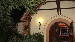Un bâtiment rustique avec une façade en bois, une entrée en arc de cercle et un luminaire placé au-dessus de la porte.