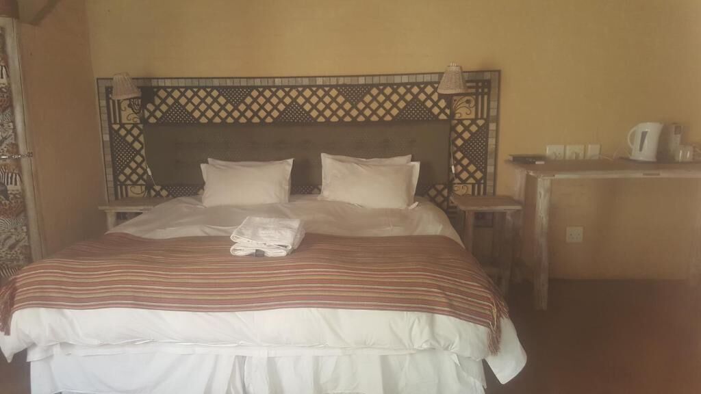 Una cama con una colcha a rayas, dos almohadas y una toalla doblada.