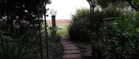 A stone pathway leading through a garden with a metal archway.