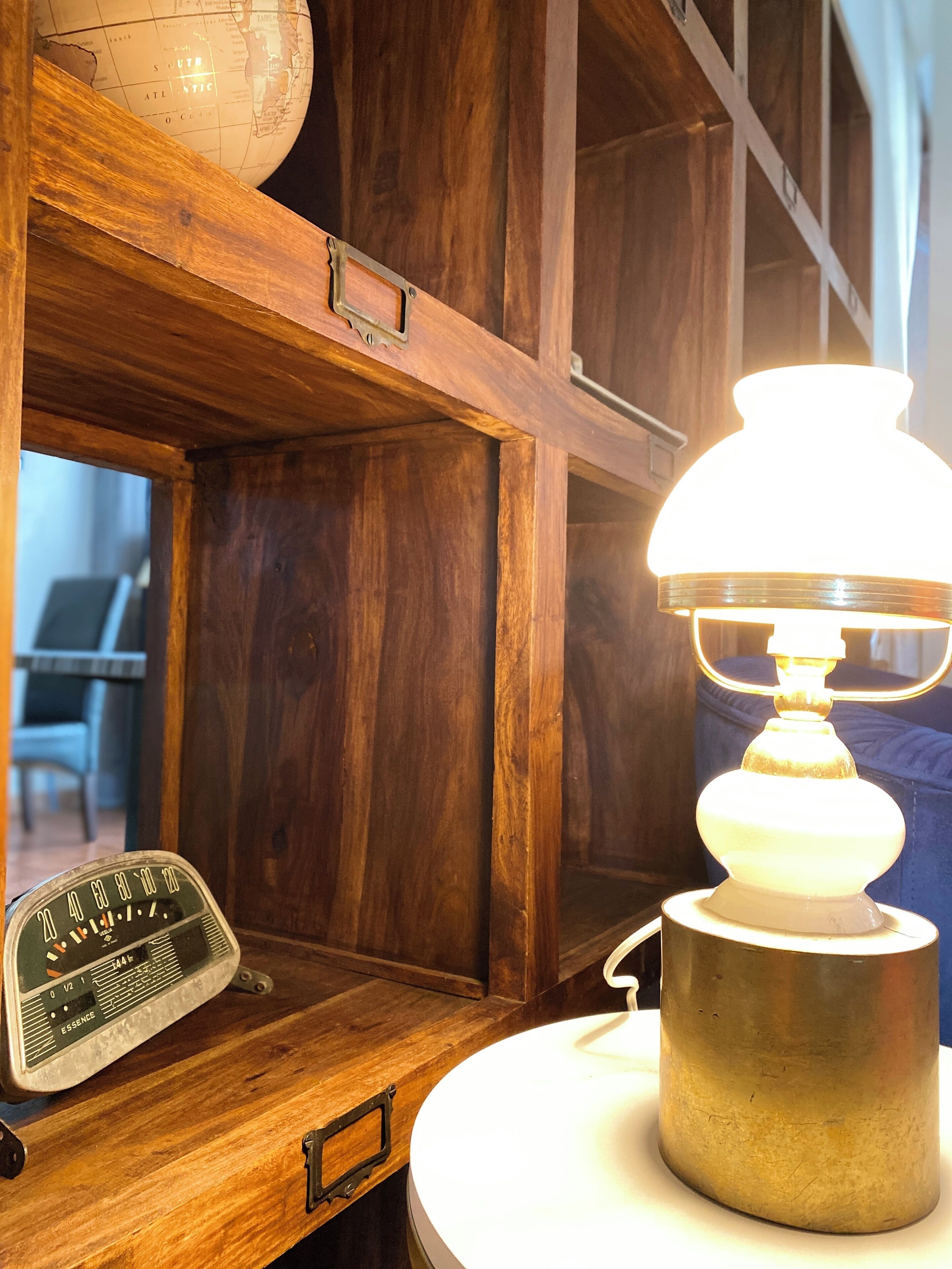 Ein Holzregal mit einem Globus, einem Vintage-Radio und einer Tischlampe.