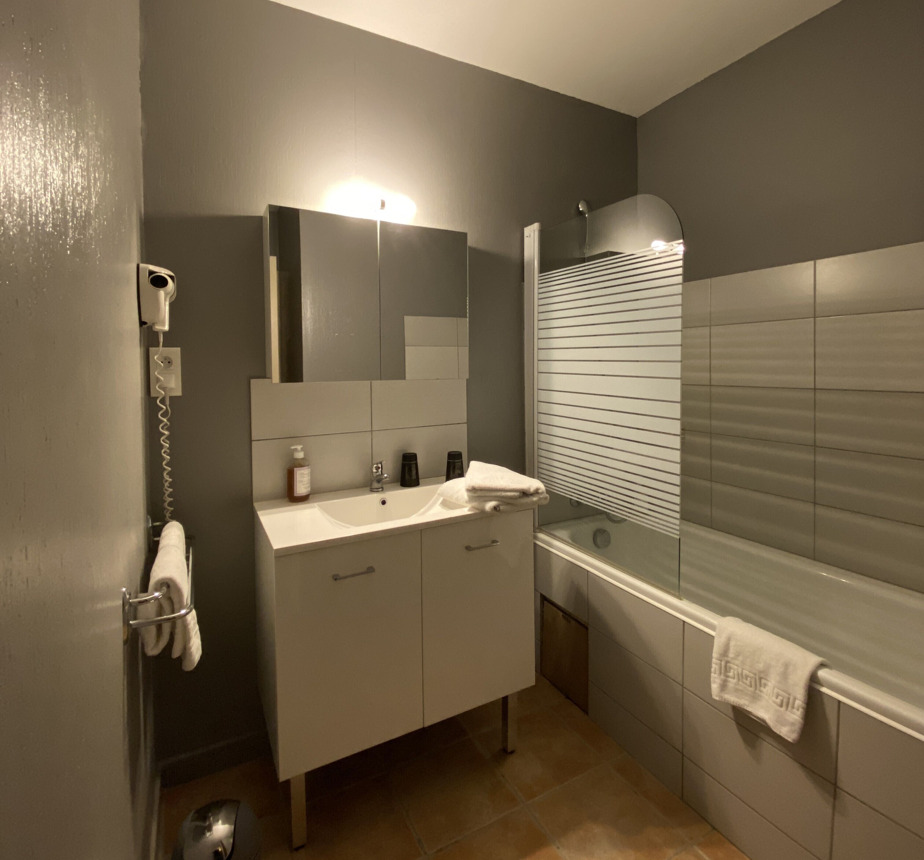 A bathroom with a sink, mirror, and bathtub.