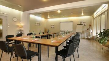 A conference room with a long table, chairs, a projector screen, and a clock on the wall.