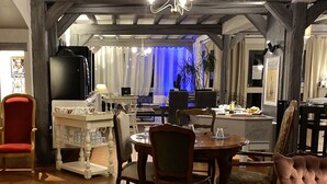 A cozy dining area with a wooden table, chairs, and a television. - Logis Hôtel Médiéval, Montélimar Nord (Rochemaure)