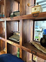 Un estante de madera con diversos objetos, incluyendo una máquina de escribir antigua, una radio y adornos.