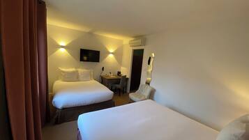 Een hotelkamer met twee bedden, een bureau, een stoel en een televisie die aan de muur hangt.