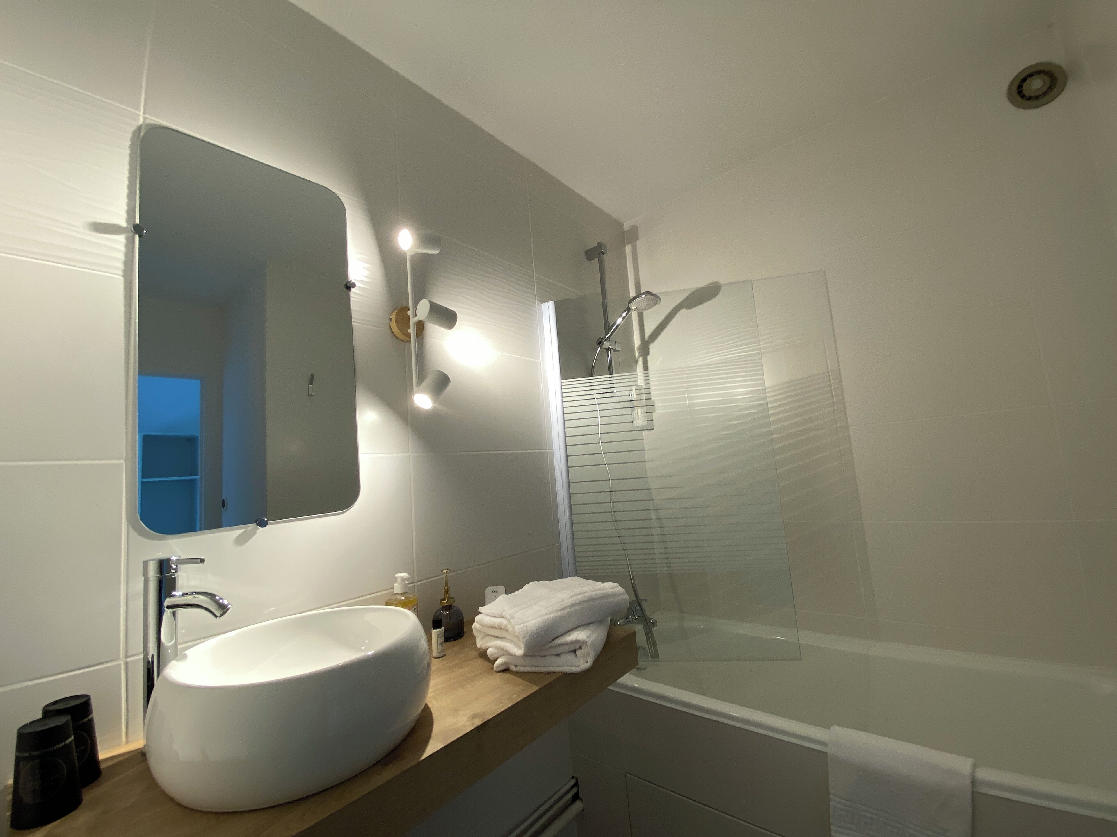 A modern bathroom with a large sink, mirror, and shower.