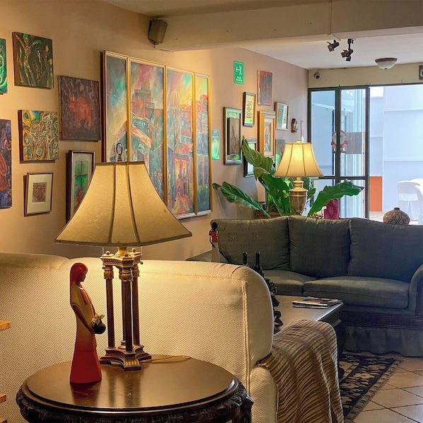 Un vestíbulo de hotel con un sofá, una mesa con lámpara y varias obras de arte enmarcadas en las paredes.