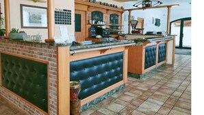 A bar area with a brick fireplace, a cushioned bench, and a tiled floor. - Hotel Agli Ulivi (Valeggio sul Mincio)