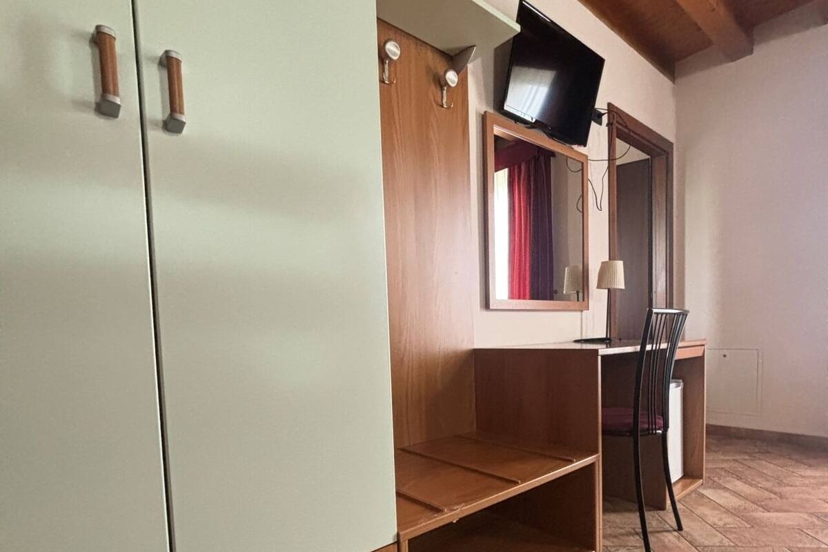 A room with a wardrobe, a desk, and a chair.