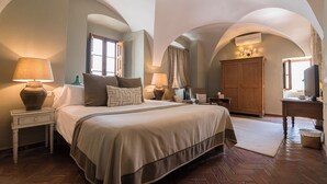 A bedroom with a large bed, two bedside tables with lamps, a wooden wardrobe, and an arched ceiling. - La Casa del Califa (Vejer de la Frontera)