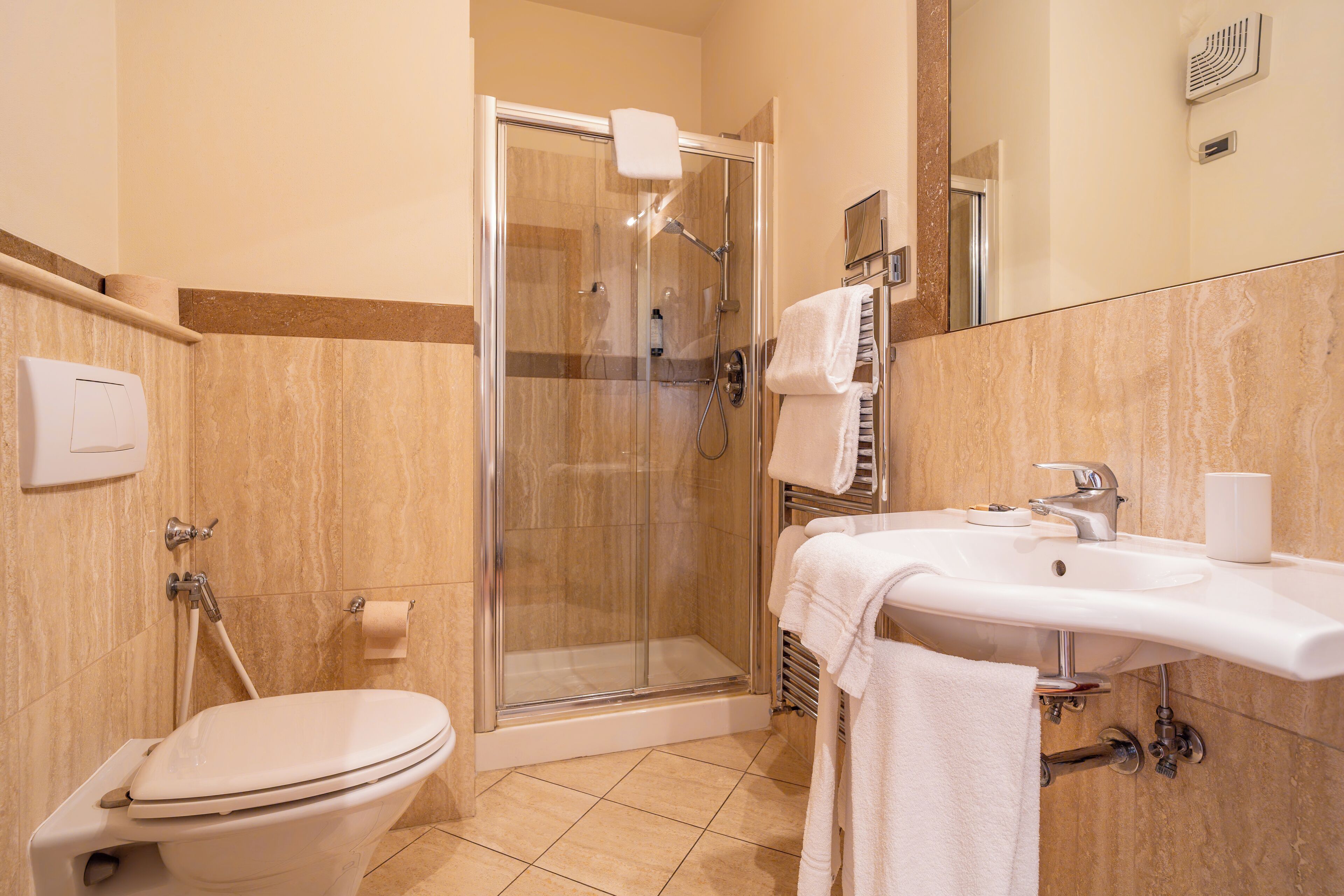 Un baño con inodoro, ducha con cerramiento de vidrio y lavamanos con espejo.
