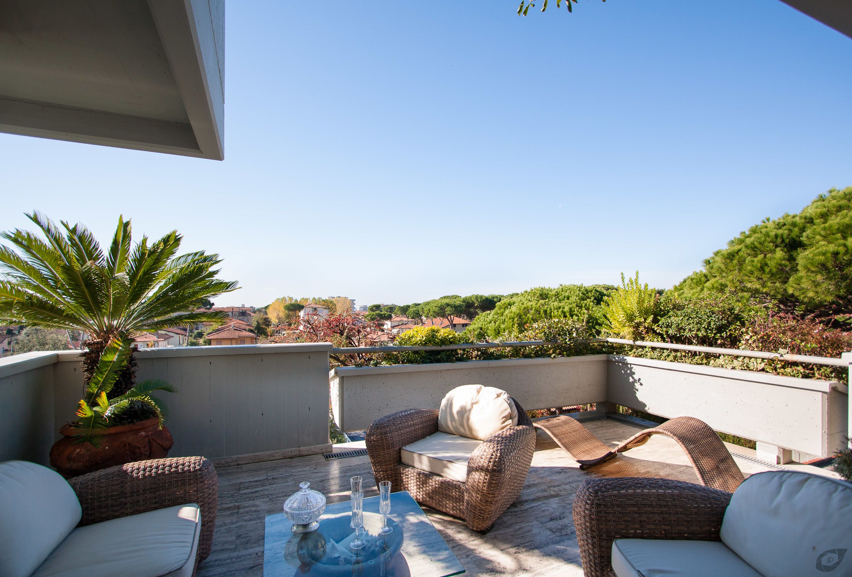 A terrace with wicker furniture, a potted plant, and a view of the landscape.