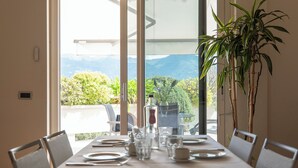 A dining table set for four with a view of mountains through large windows. - Residence Verdeluna (Pietrasanta)