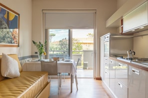 Eine moderne Küche mit Essbereich, einer Couch und Blick ins Freie.