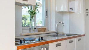 A modern kitchen with a gas stove, stainless steel sink, and white cabinetry. - Residence Verdeluna (Pietrasanta)