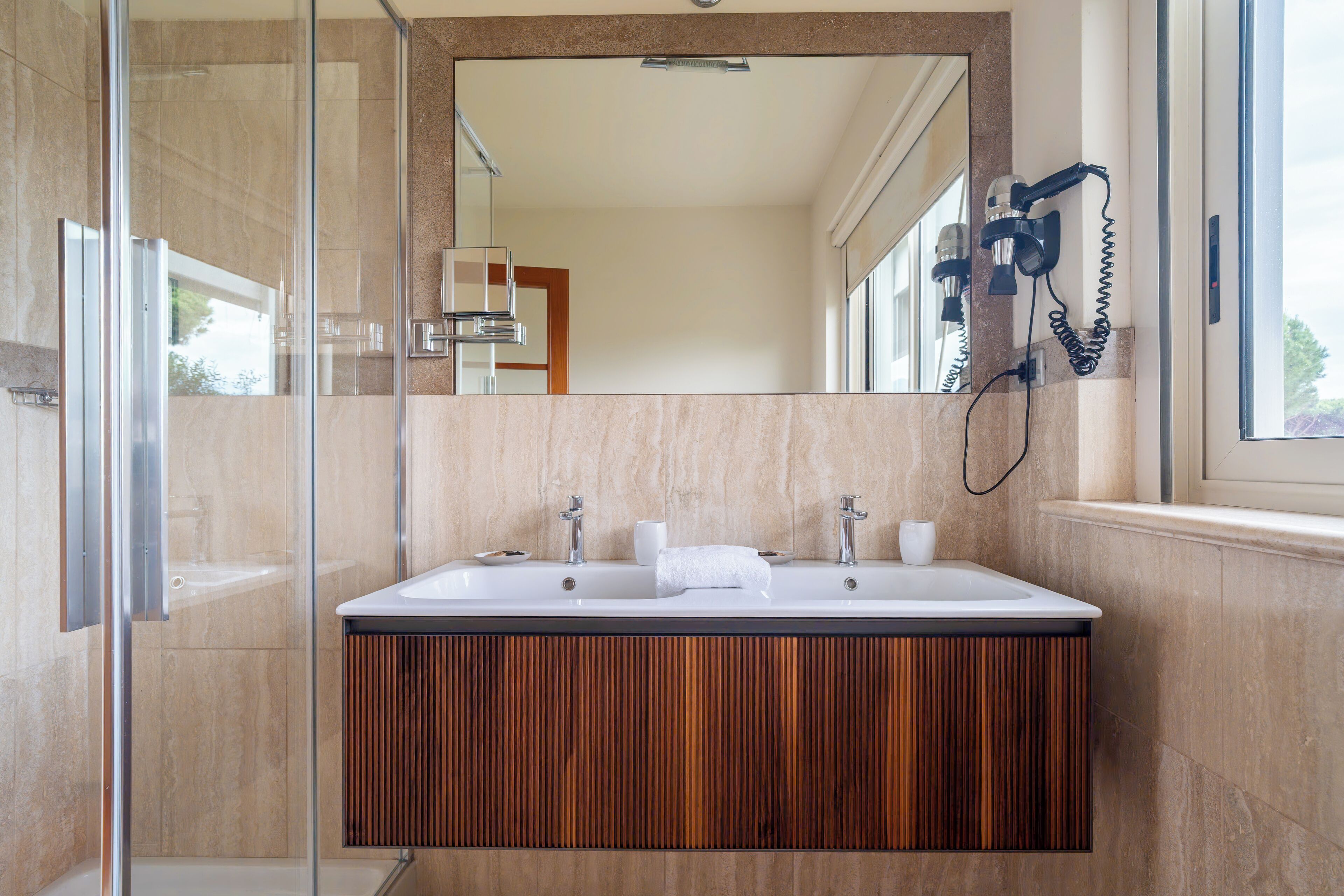A modern bathroom with a large sink, wooden vanity, and a glass shower enclosure.
