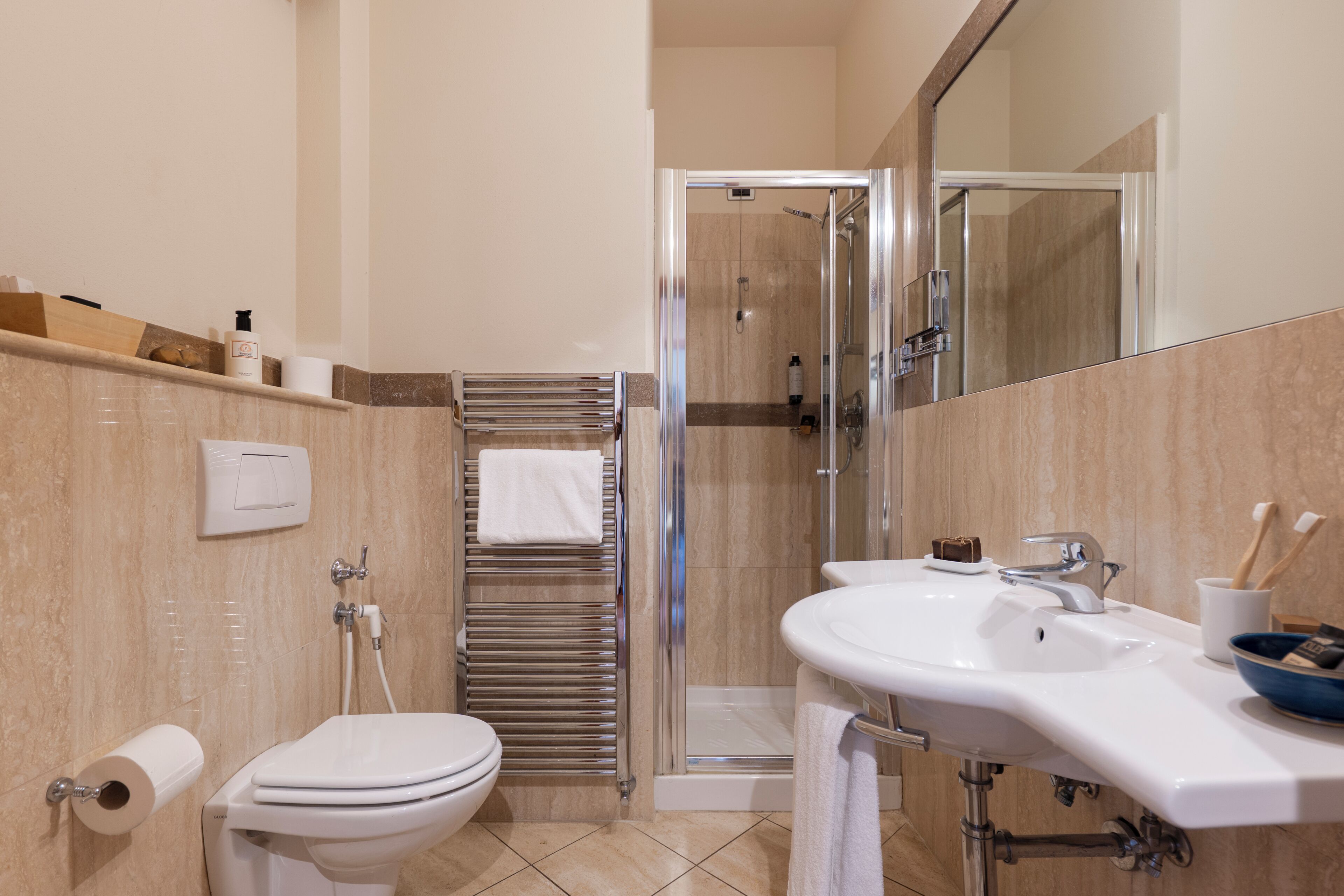 Een badkamer met toilet, wastafel, douche en spiegel.