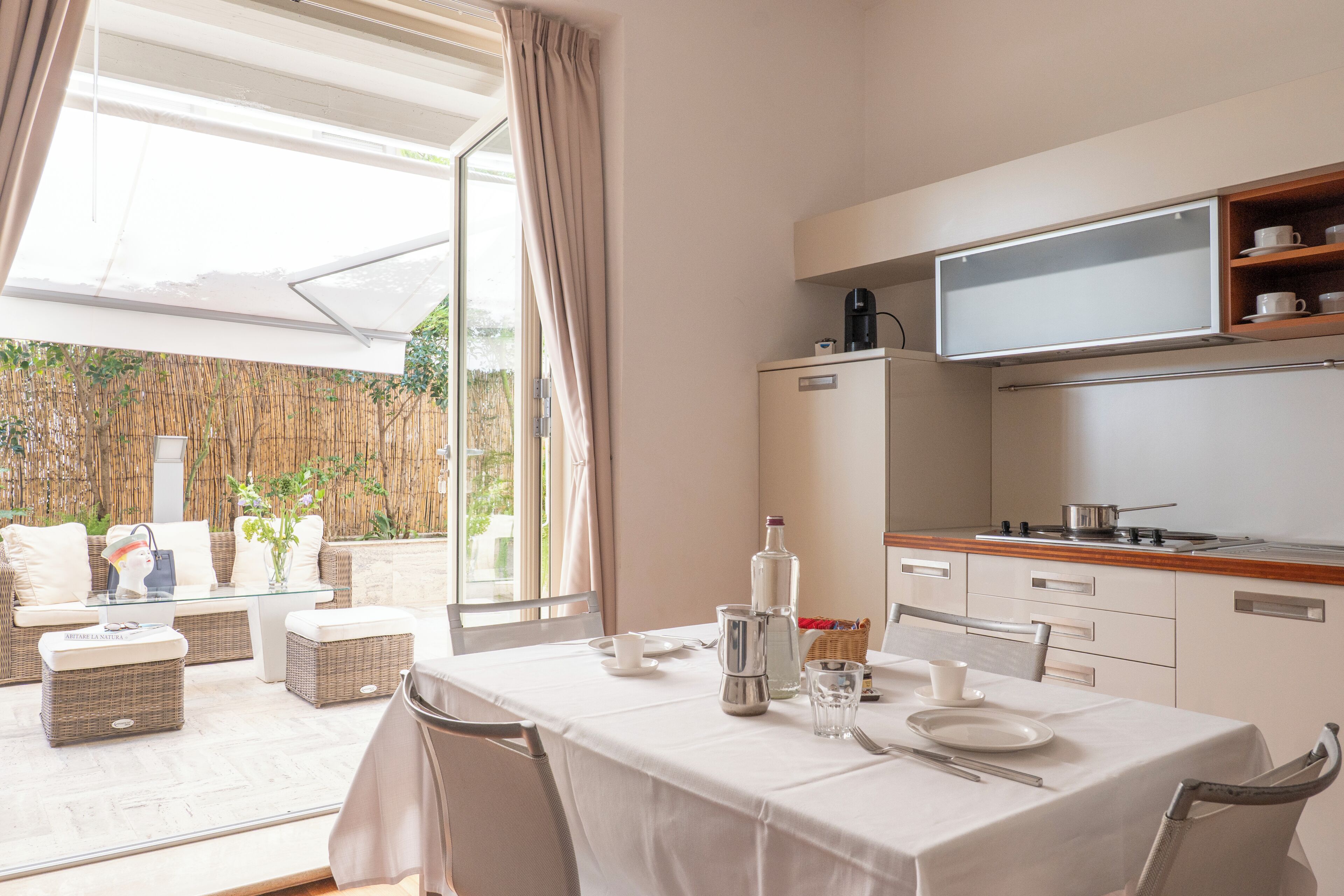 Un comedor con una mesa preparada para dos, una cocina con microondas y cafetera, y vistas al exterior.