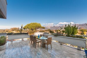 Eine Terrasse mit rundem Tisch und Stühlen mit Blick auf eine gebirgige Landschaft.
