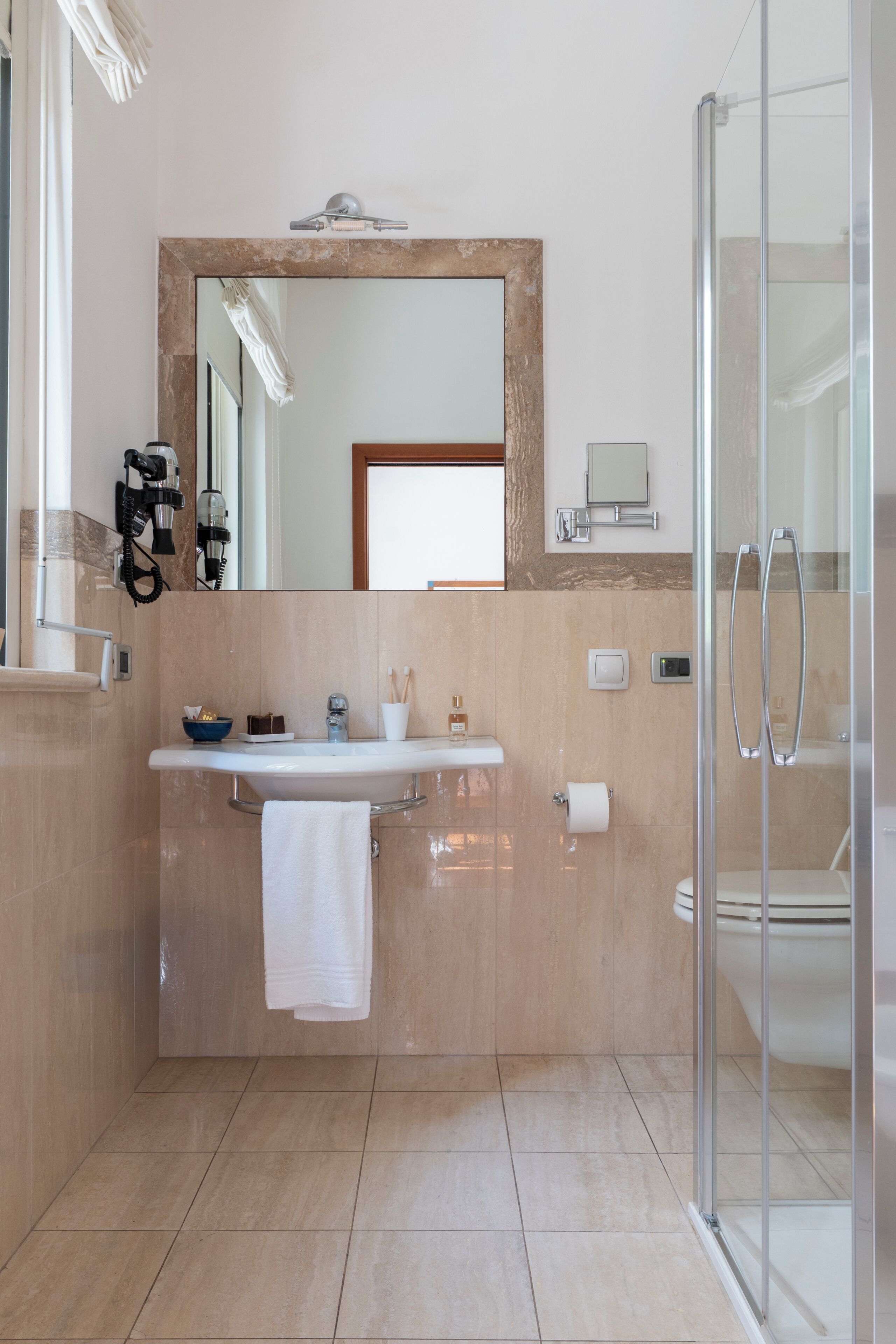 Une salle de bain moderne avec un grand miroir, un lavabo, une douche en verre et une serviette accrochée au mur.