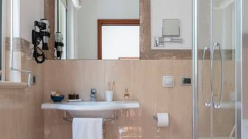 Une salle de bain moderne avec un grand miroir, un lavabo, une douche en verre et une serviette accrochée au mur.