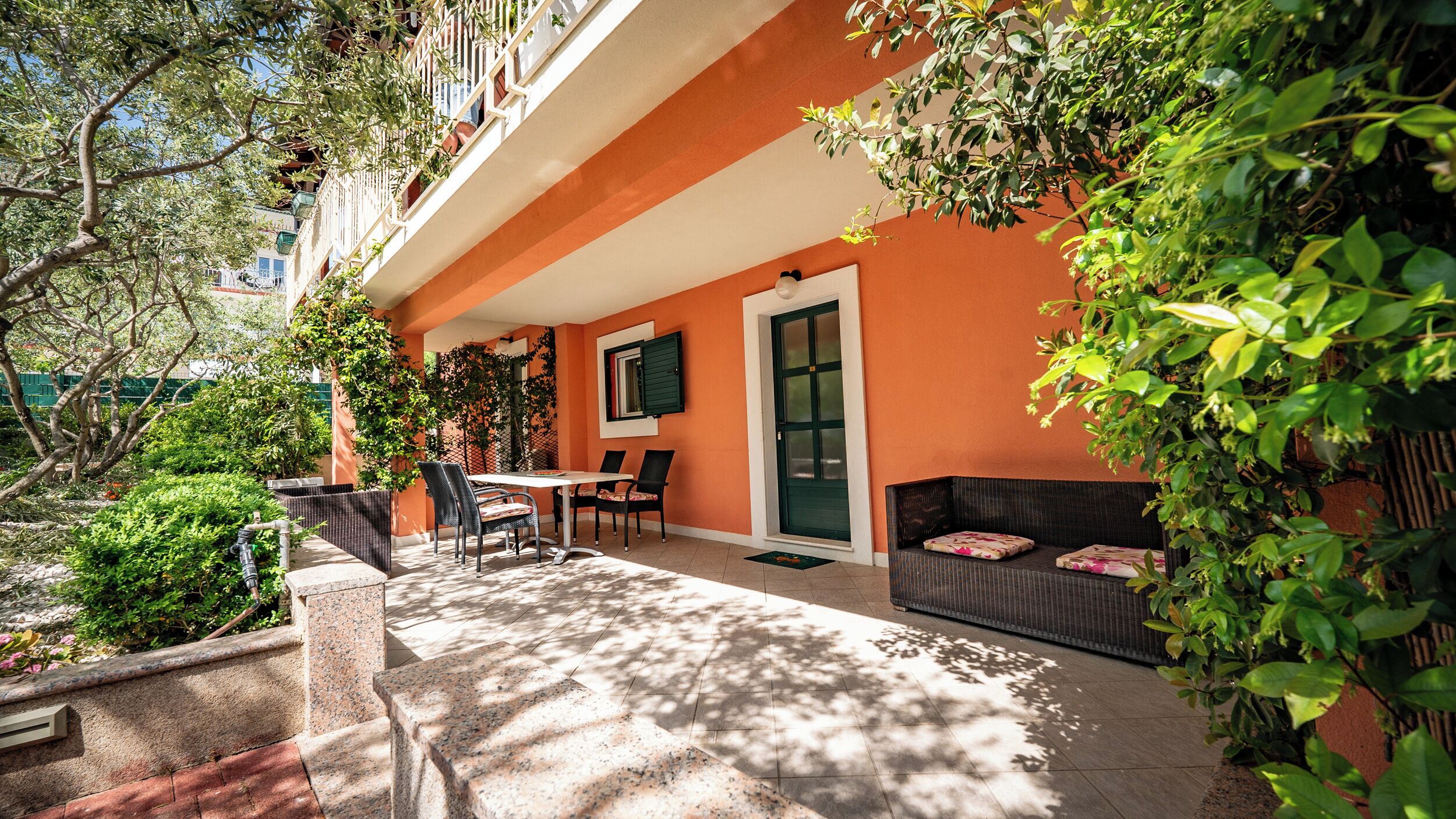 An outdoor patio with a table and chairs, a sofa, and a door.