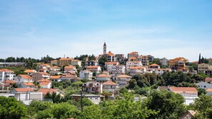 A hillside town with a prominent church tower, terraced houses, and lush greenery. - Villa Rustica Dalmatia Apartments (Seget)