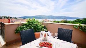 A balcony with a table set for two, a bottle of wine, and a plate of strawberries.