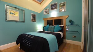 A bedroom with a bed, a nightstand, a lamp, and wall-mounted shelves. - The PitStop (Bishop's Stortford)