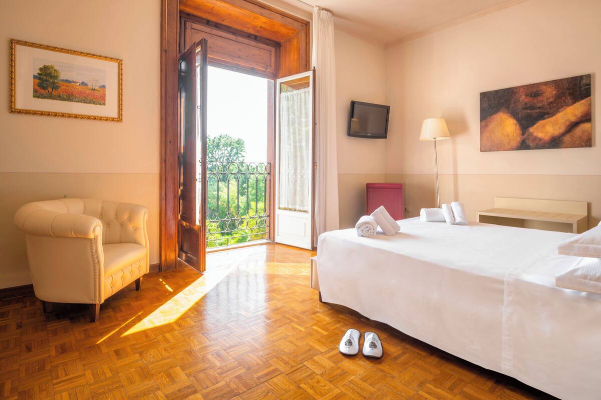 Une chambre d’hôtel avec un lit, une chaise, une télévision et un tableau.