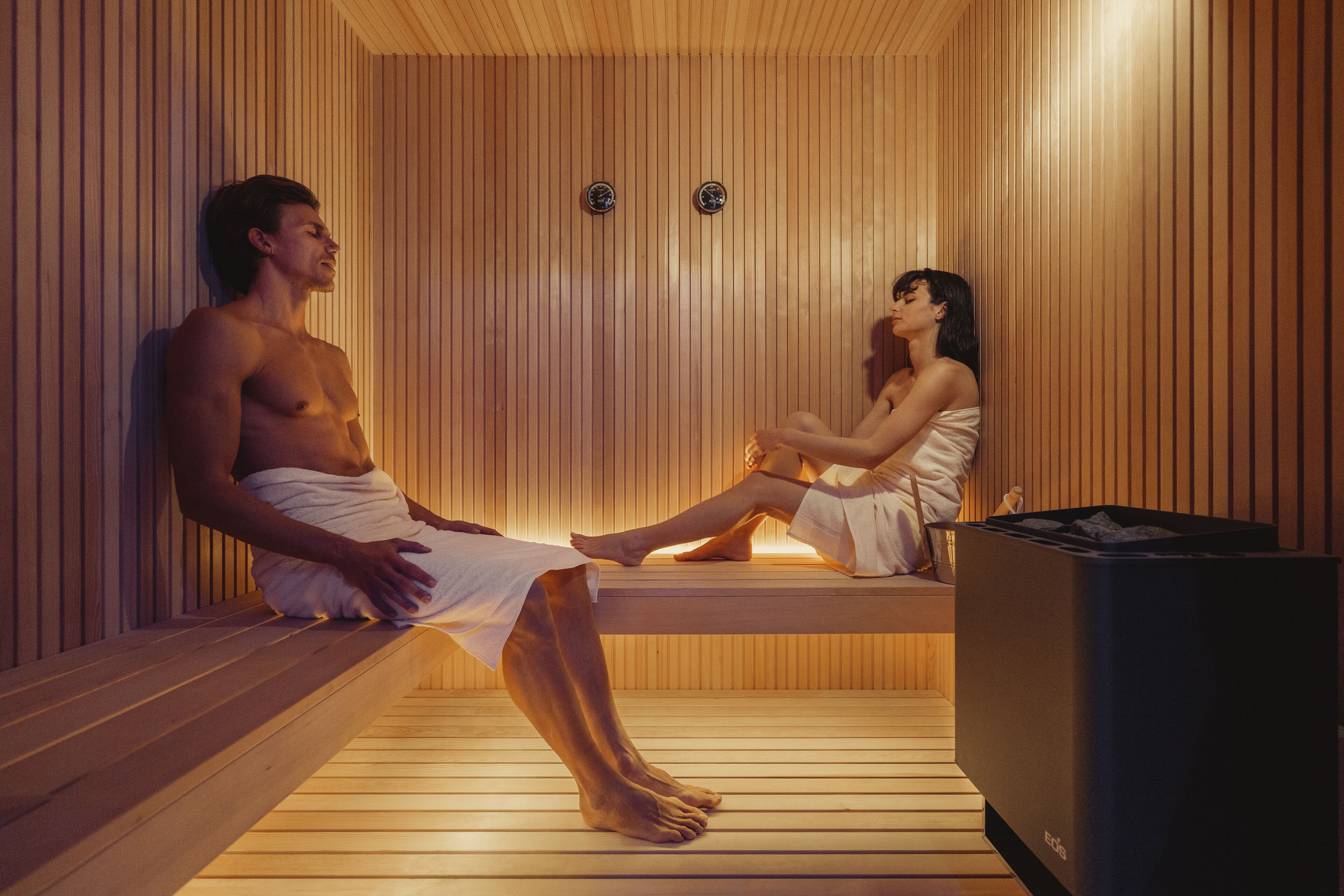 Una sauna con pareti e panche in legno, un riscaldatore e un televisore.