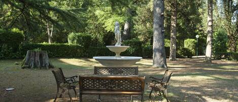 Un parque con una fuente, bancos y un tocón de árbol.