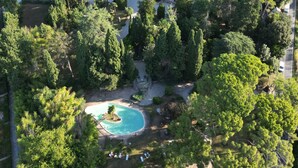 An aerial view of a large estate with a central building surrounded by lush greenery, a swimming pool, and a well-maintained garden. - Villa Quiete (Montecassiano)