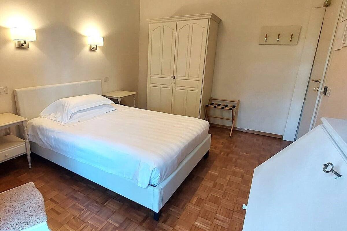 Une chambre à coucher comprenant un lit, des tables de chevet, une armoire et un bureau.