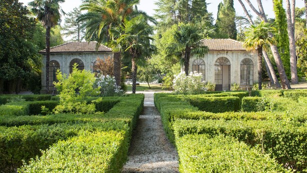A garden with a gravel path leading to a building with arched windows. - Villa Quiete (Montecassiano)