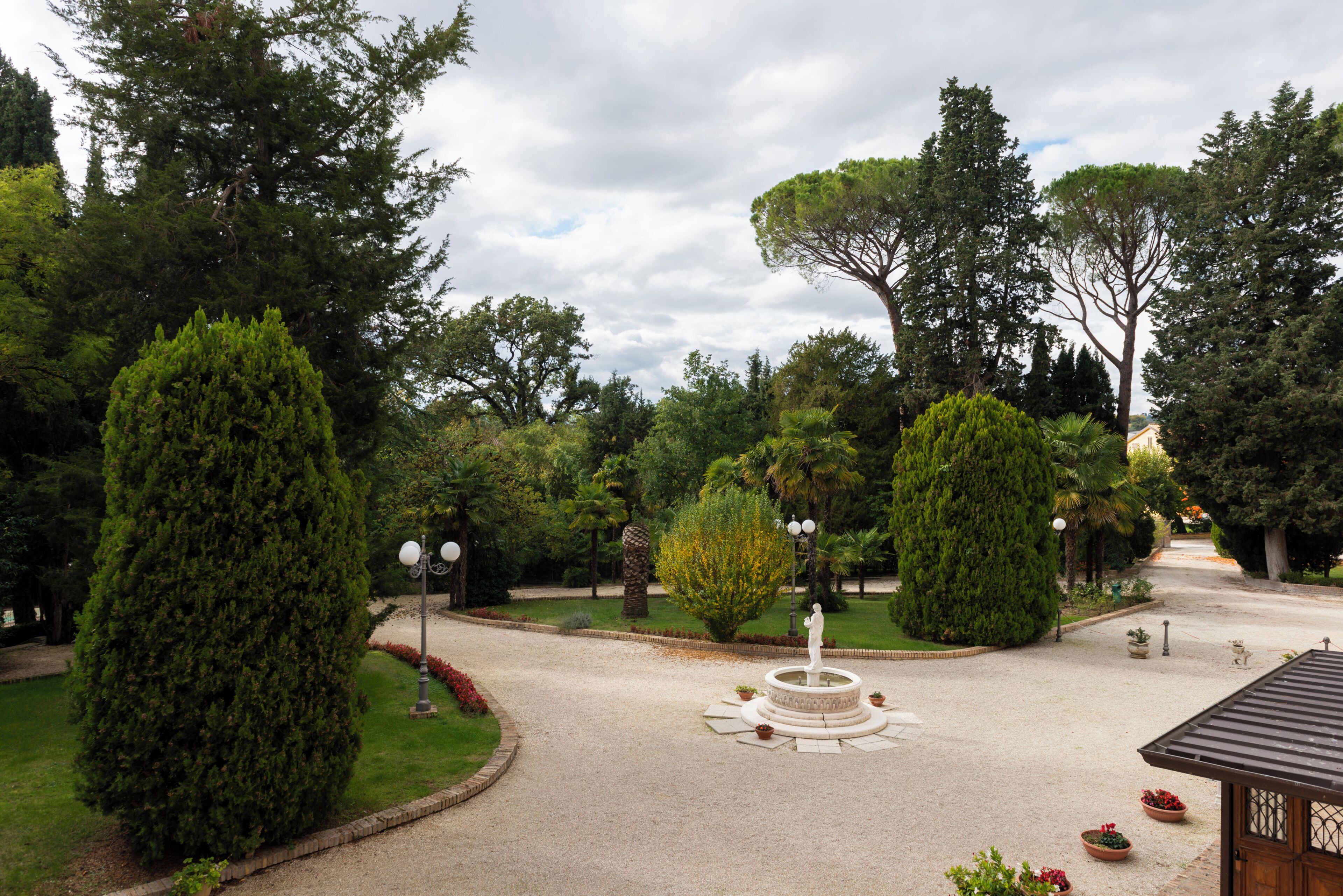 Un jardin avec une fontaine centrale, entouré de différents arbres et arbustes.