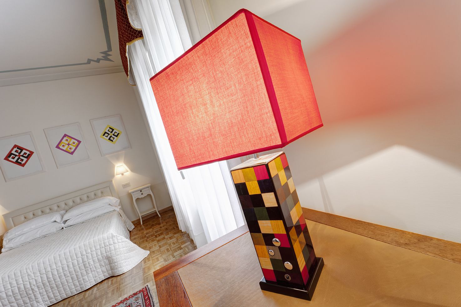 Une chambre d’hôtel avec un lit, une table de chevet, une lampe et des œuvres d’art accrochées au mur.