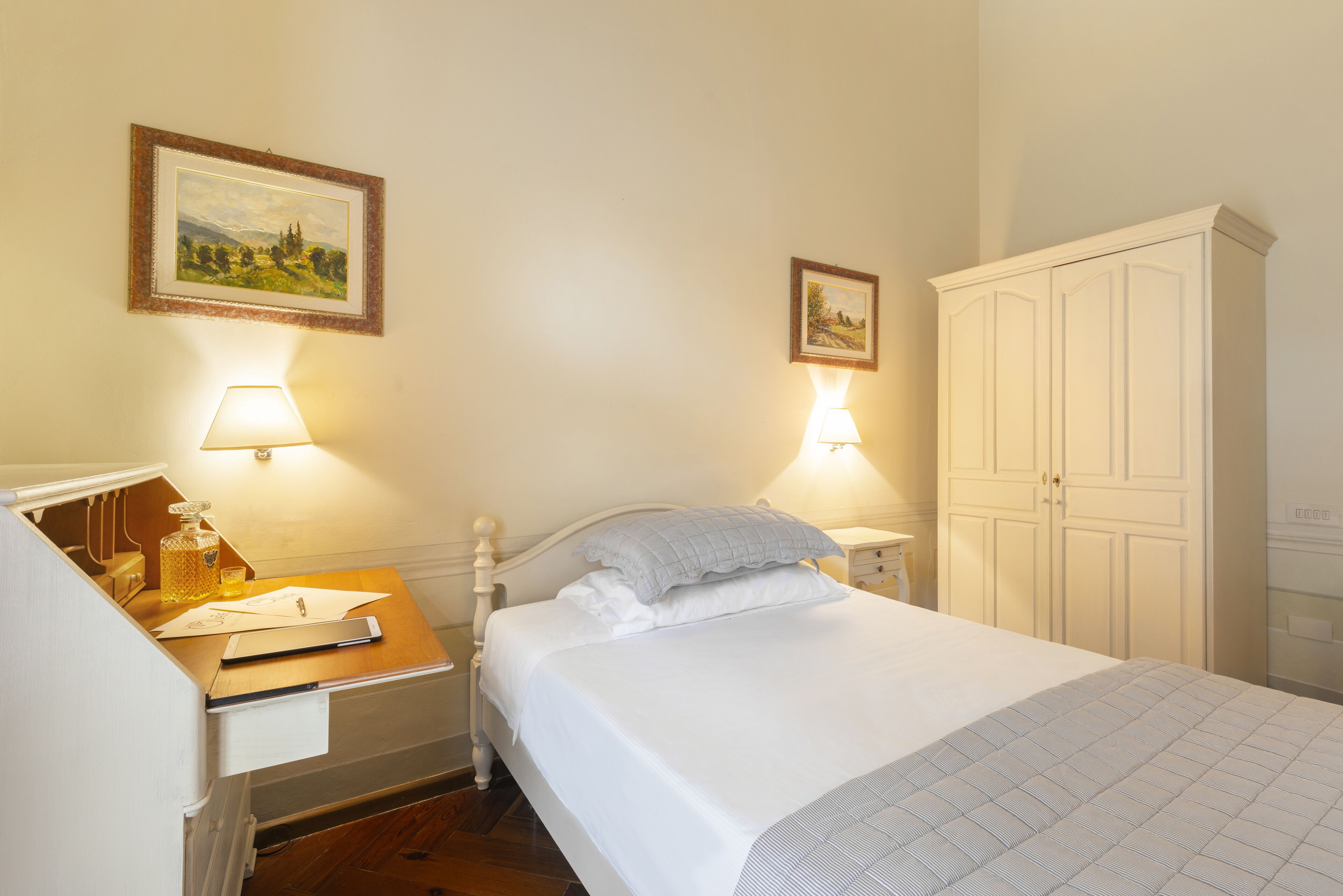 A bedroom with a bed, bedside tables, a desk, and a wardrobe.