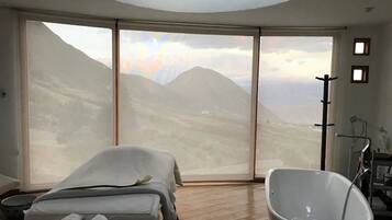 Relax in this serene space with a bathtub and massage table, offering breathtaking views of the surrounding mountains.