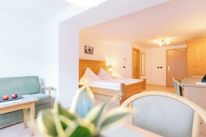 A hotel room with a bed, a desk, a chair, a sofa, and a small table with apples. - Ganis Resort (Nova Ponente)