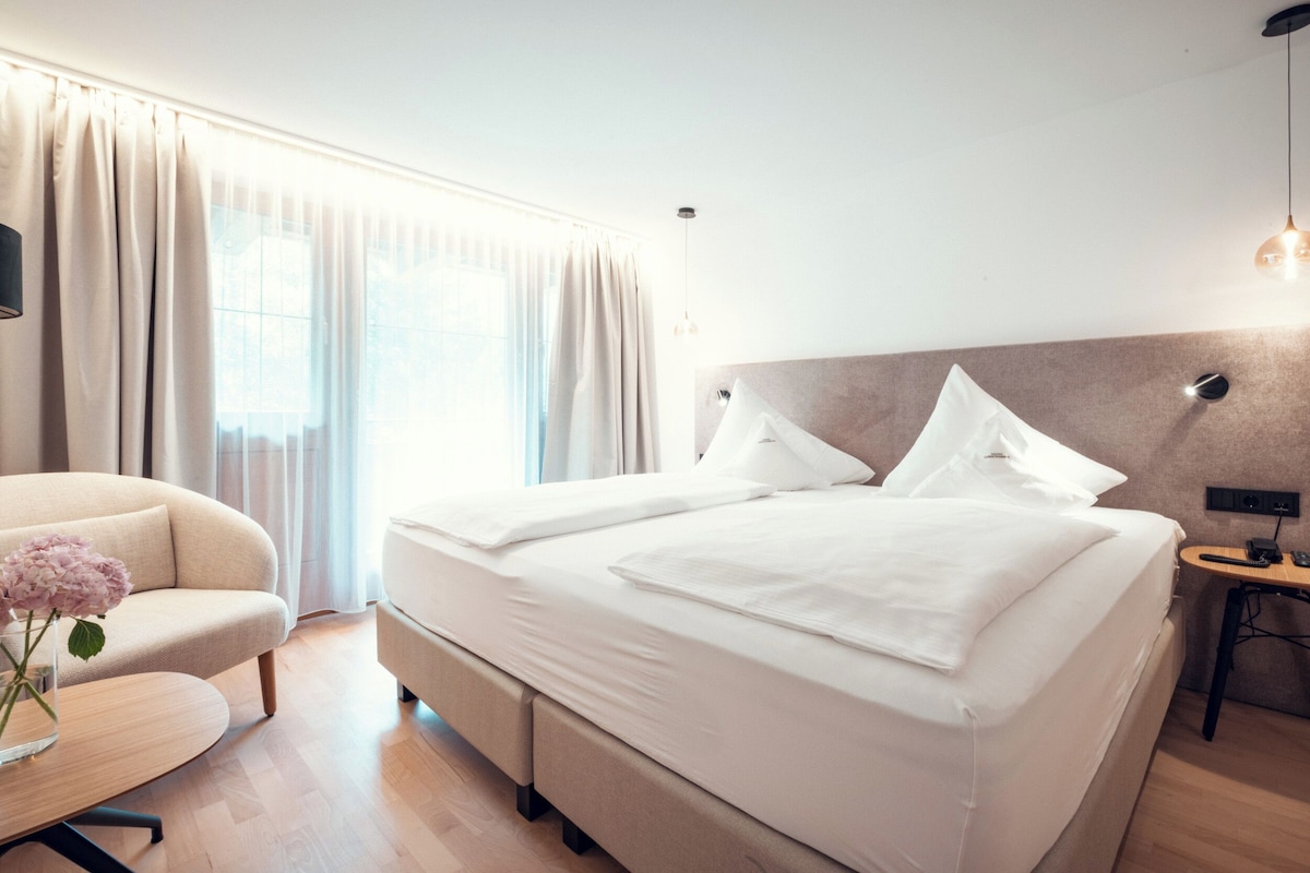 Una habitación de hotel moderna con una cama grande, un sofá, una mesita y un escritorio.