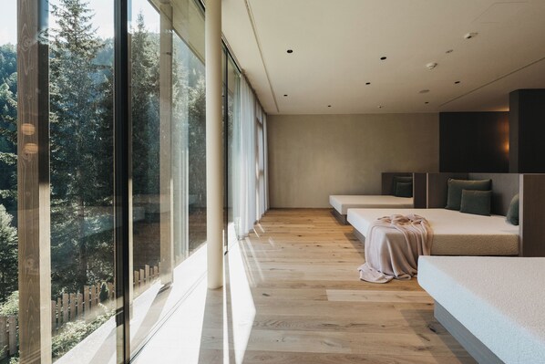 Quarto de hotel moderno com uma janela grande, piso de madeira e uma cama com cobertor.