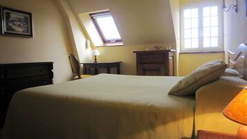 Una camera da letto con un letto grande, una scrivania, una sedia, un comodino, una lampada, una finestra e un quadro appeso al muro.