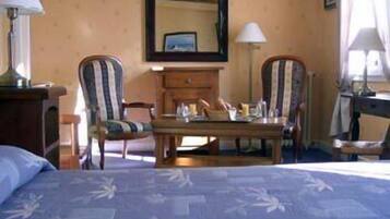 Une chambre d’hôtel avec un lit, deux chaises, une table et une commode.