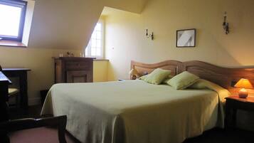 A bedroom with a bed, a desk, a chair, a nightstand, and a window.