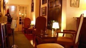 A hotel lobby with a wooden floor, a reception desk, and several armchairs. - Hostellerie de la Bouriane (Gourdon)