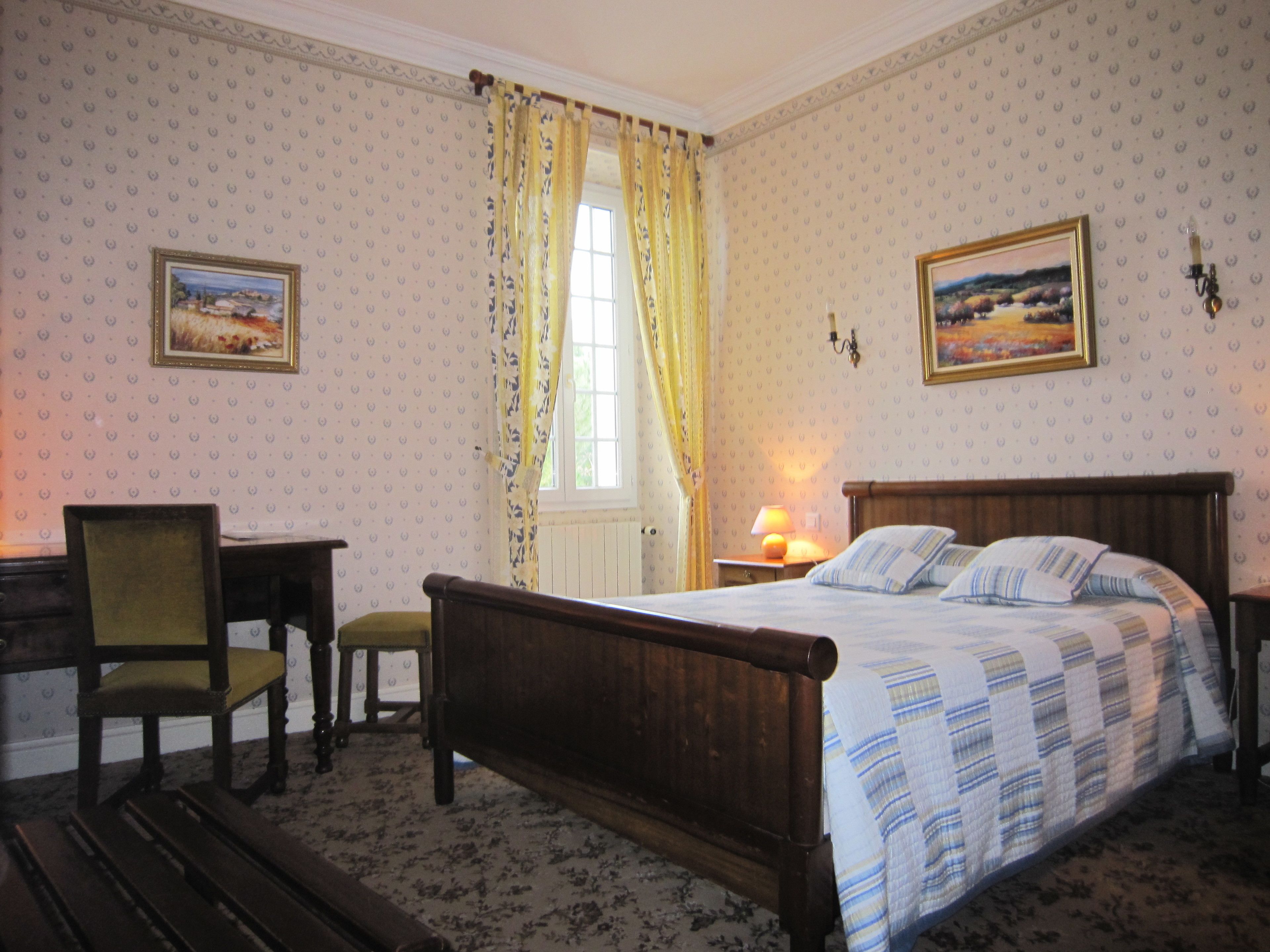 Un dormitorio con una cama de madera, una silla, una mesita de noche y una ventana con cortinas.