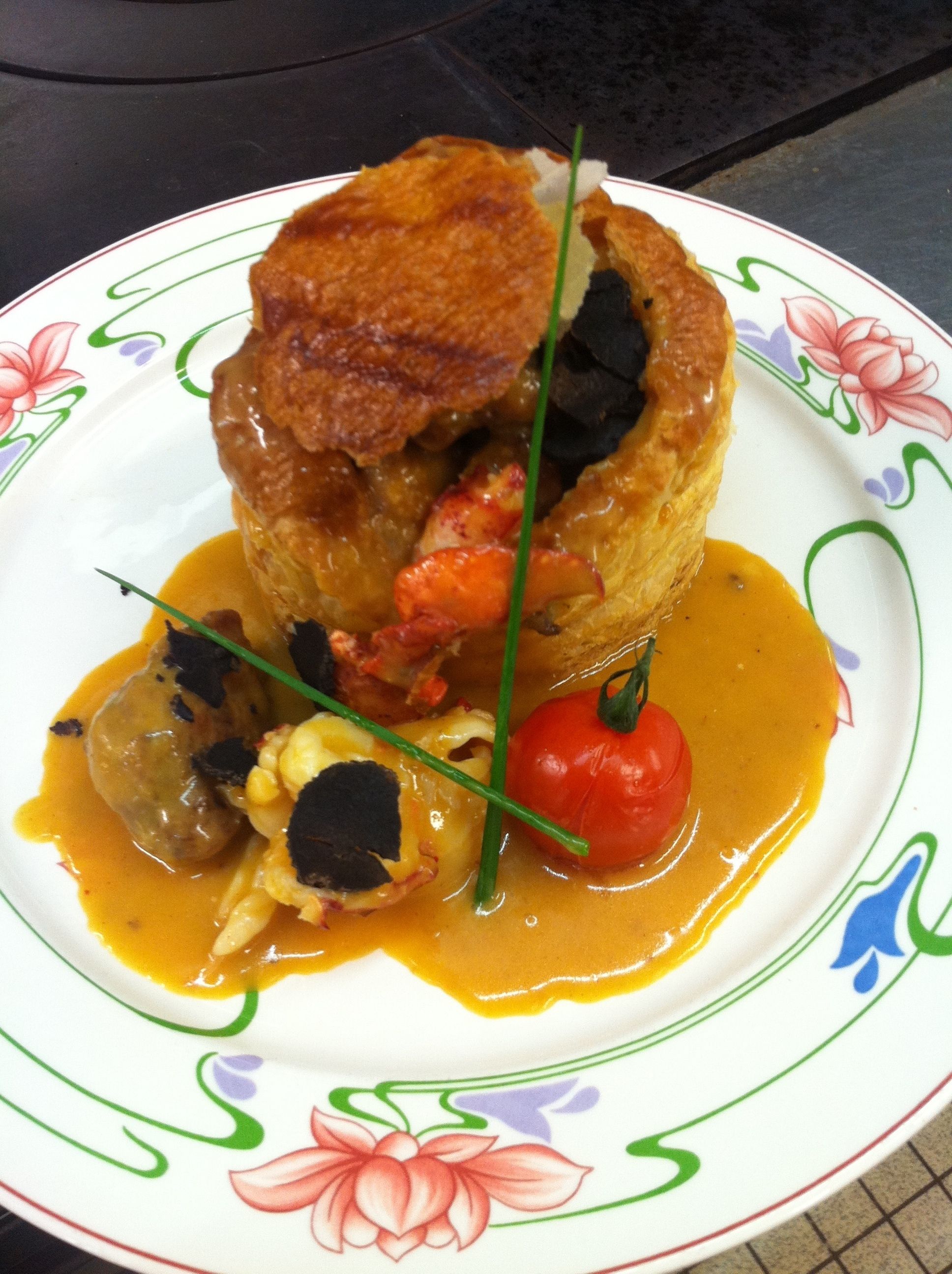 A plate of food with a pastry, vegetables, and sauce.